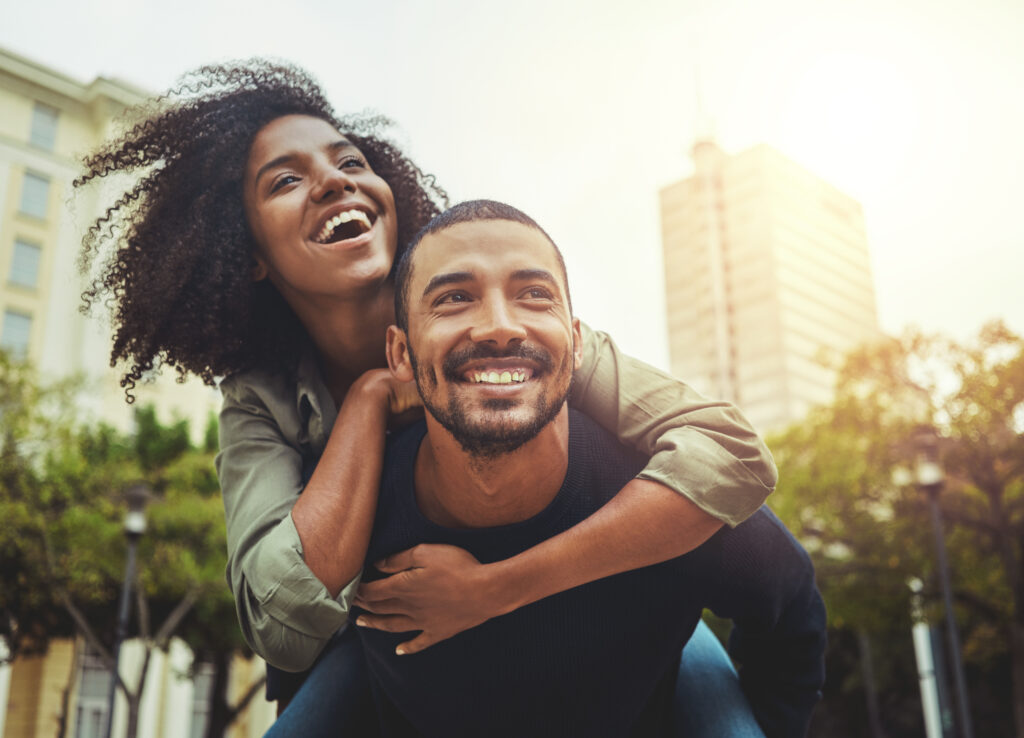 African American man giving woman a piggy back ride